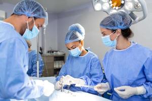 urgente chirurgia. professionale inteligente intelligente chirurghi in piedi vicino il paziente e l'esecuzione un operazione mentre Salvataggio il suo vita foto