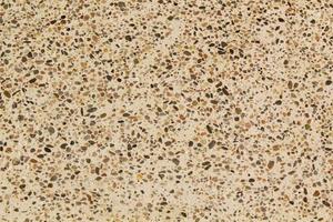 calcestruzzo beige pavimento con multicolore marmo e piccolo naturale schiacciato pietre inserito. ciottoli strutturato sfondo. decorativo ruvido superficie granito. ghiaia parete Materiale. poco roccia fondale foto