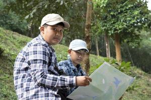 asiatico ragazzi utilizzando binocolo per fare il osservazione uccelli nel tropicale foresta durante estate campo, idea per apprendimento creature, natura animali e insetti al di fuori il aula. foto