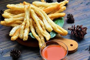 un' piatto di cakwe o torta con peperoncino salsa a di legno tavolo. cakwe è un' popolare tradizionale merenda a partire dal Cinese e Indonesia foto