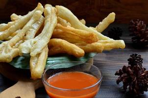 un' piatto di cakwe o torta con peperoncino salsa a di legno tavolo. cakwe è un' popolare tradizionale merenda a partire dal Cinese e Indonesia foto