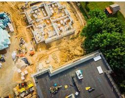 aereo vicino su nuovo costruzioni vero tenuta sviluppo luogo. urbano costruzione luogo, aereo Visualizza. tetti e edificio costruzione luogo con lavoratore posa Materiale. foto