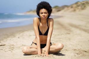 grave nero donna con afro capelli nel bikini vicino mare foto