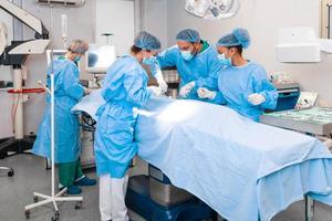 un' del chirurgo squadra nel uniforme esegue un operazione su un' paziente a un' cardiaco chirurgia clinica. moderno medicinale, un' professionale squadra di chirurghi, Salute. foto