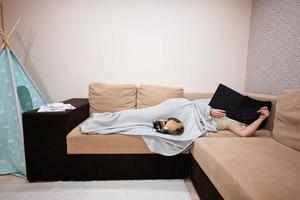 giovane donna dire bugie nel letto a casa e leggere libro con sua gatto. foto