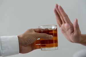 uomo rifiuta dire no e evitare per bevanda un alcool whisky , sosta mano cartello maschio, alcolismo trattamento, alcool dipendenza, smettere liquore, fermare potabile alcol. rifiuto bicchiere liquore, malsano, rifiutare foto