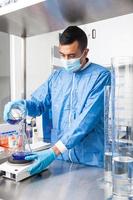 giovane maschio scienziato Lavorando con un agitatore a laboratorio vestito nel blu foto