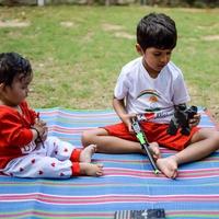 Due contento ragazzi nel società parco, contento asiatico fratelli chi siamo sorridente felicemente insieme. fratelli giocare all'aperto nel estate, migliore gli amici. bambino piccolo bambino ragazzo giocando con il suo contento fratello nel il giardino foto