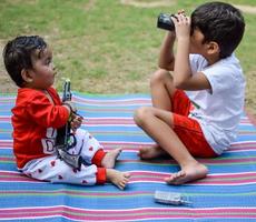 Due contento ragazzi nel società parco, contento asiatico fratelli chi siamo sorridente felicemente insieme. fratelli giocare all'aperto nel estate, migliore gli amici. bambino piccolo bambino ragazzo giocando con il suo contento fratello nel il giardino foto