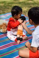 Due contento ragazzi nel società parco, contento asiatico fratelli chi siamo sorridente felicemente insieme. fratelli giocare all'aperto nel estate, migliore gli amici. bambino piccolo bambino ragazzo giocando con il suo contento fratello nel il giardino foto