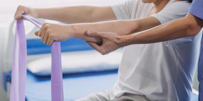 medico o fisioterapista Lavorando l'esame trattamento ferito braccio di atleta maschio paziente, allungamento e esercizio, fare il reinserimento terapia dolore nel clinica. foto