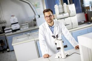 giovane scienziato in camice bianco che lavora con il microscopio binoculare nel laboratorio di scienza dei materiali