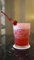 un' bicchiere di fragola succo a il tavolo con un' fantasia cannuccia. foto