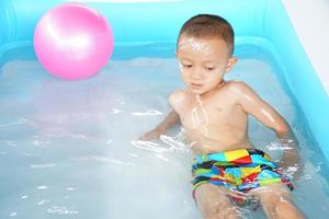 caldo tempo atmosferico. ragazzo giocando con acqua felicemente nel il vasca. foto