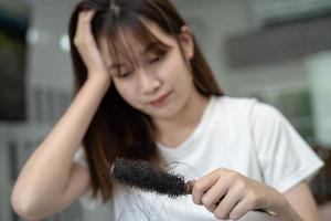 la donna asiatica ha problemi con la caduta dei capelli lunghi attaccata alla spazzola del pettine. foto