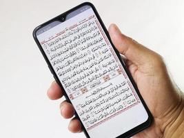 mano Tenere mobile Telefono mostrando Corano applicazione nel esso. Corano recitazione su sura al-Kahfi. foto