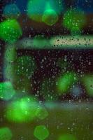 gocce di pioggia e luci bokeh sulla finestra foto