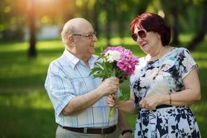 contento anziano coppia con fiori. bello uomo e donna anziano cittadini. marito e moglie di vecchio età per un' camminare. foto