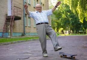 un anziano uomo impara per cavalcata un' skateboard. un' moderno pensionato. foto