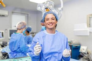 ritratto di contento donna chirurgo in piedi nel operativo camera, pronto per opera su un' paziente. femmina medico lavoratore nel chirurgico uniforme nel operazione Teatro. foto