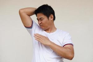 asiatico uomo controlli il suo corpo odore durante lui si sente piccante, solleva giusto braccio su, odori il suo ascella, ascellare. concetto , Salute problema. sgradevole corpo odore , odore cattiva reazione. negativo emozione. foto