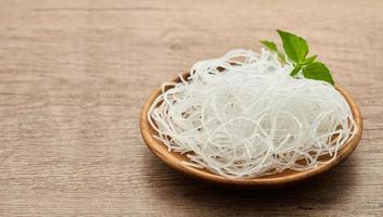 asiatico vermicelli o cellofan spaghetto nel di legno piatto su legna tavolo sfondo. bicchiere spaghetto foto