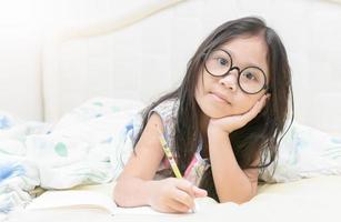 asiatico ragazza scrittura per diario su il letto foto