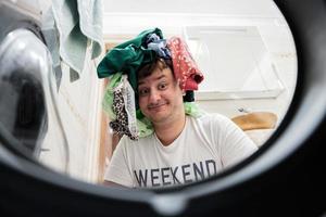 divertente uomo Visualizza a partire dal lavaggio macchina dentro. maschio fa lavanderia quotidiano routine. foto