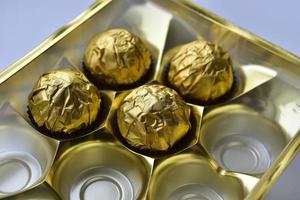 caramelle al cioccolato in una scatola in un involucro d'oro foto