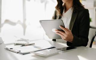 fiducioso donna d'affari Lavorando su computer portatile, tablet e tavoletta a sua posto di lavoro a ufficio. foto