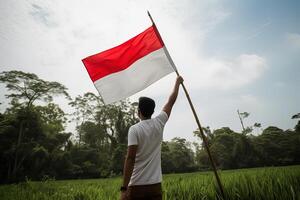 un' uomo Tenere un' rosso e bianca Indonesia bandiera su superiore di un' lussureggiante verde riso campo. ai generato foto