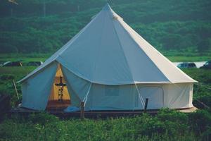 tenda bianca in un campo con cielo blu nuvoloso foto