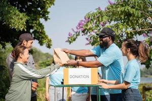 squadra di volontari Tenere donazioni scatole nel all'aperto. volontari mettendo cibo nel donazione scatole, sociale lavoratore fabbricazione Appunti beneficenza foto