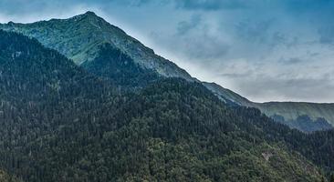 paesaggio con montagne e foreste con un cielo blu nuvoloso in abkhazia foto