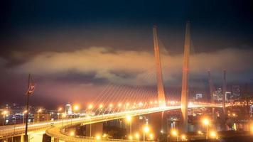 illuminato ponte d'oro con cielo nuvoloso di notte a vladivostok, russia foto