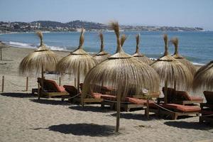 sabbioso spiaggia e cannuccia gli ombrelli, mare nel sfondo foto