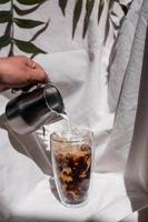 barista che versa il latte in un bicchiere di caffè freddo