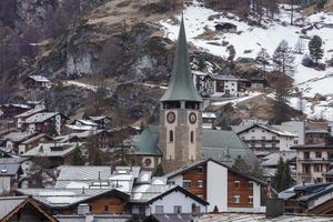 orologio Torre in mezzo edifici contro montagna durante inverno foto