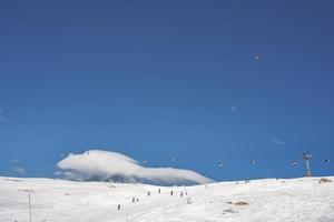 sciatori sciare su versante e sciare sedia ascensori al di sopra di nevoso montagna foto