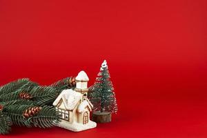 Natale carta. Natale albero e carino Villetta su un' rosso sfondo. foto