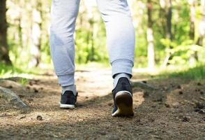 un' uomo passeggiate nel il foresta. scarpe da ginnastica avvicinamento foto