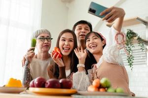 contento famiglia asiatico famiglia assunzione selfie con smartphone insieme cucinando cibo nel il cucina. la spesa tempo insieme cucinare insieme nel il cucina e cenare insieme felicemente foto