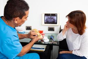 bellissimo donna ricevente spiegazioni di sua dentale trattamento con sua dentista. medico utilizzando un' umano cranio come modello. foto