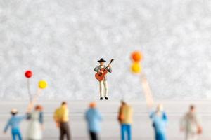 miniatura musicista giocando un' chitarra su palcoscenico, mondo musica giorno concetto foto