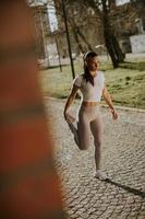 bella giovane donna che si estende durante l'allenamento nell'ambiente urbano foto