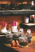 caffè fagioli nel bicchiere bottiglie su di legno contatore nel caffetteria foto