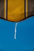 un ghiacciolo contro un' blu cielo sospeso a partire dal un' giallo tenda foto