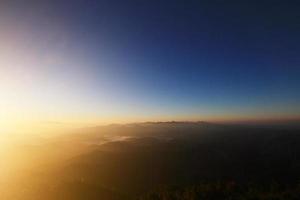 bellissimo d'oro naturale luce del sole e crepuscolo di Alba splendente per nel il nebbia su valle di montagna nel Tailandia foto
