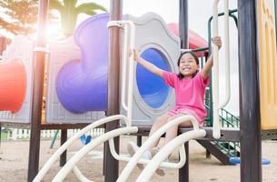 contento asiatico ragazza giocando su bambini terreno di gioco foto