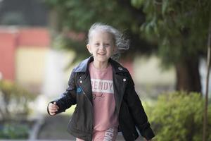 sorridente ragazza a partire dal scuola materna per un' camminare. foto